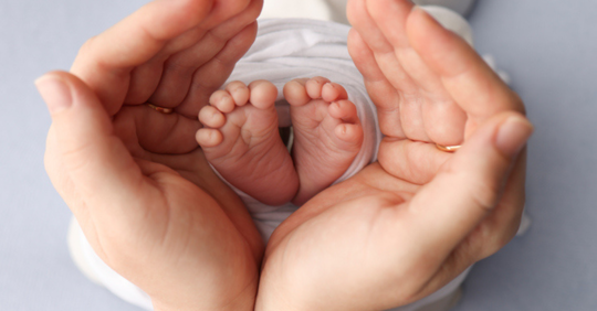 Mom hands holding little baby's feet
