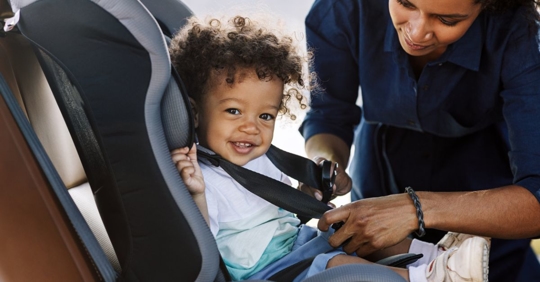Mom strapping child into car seat